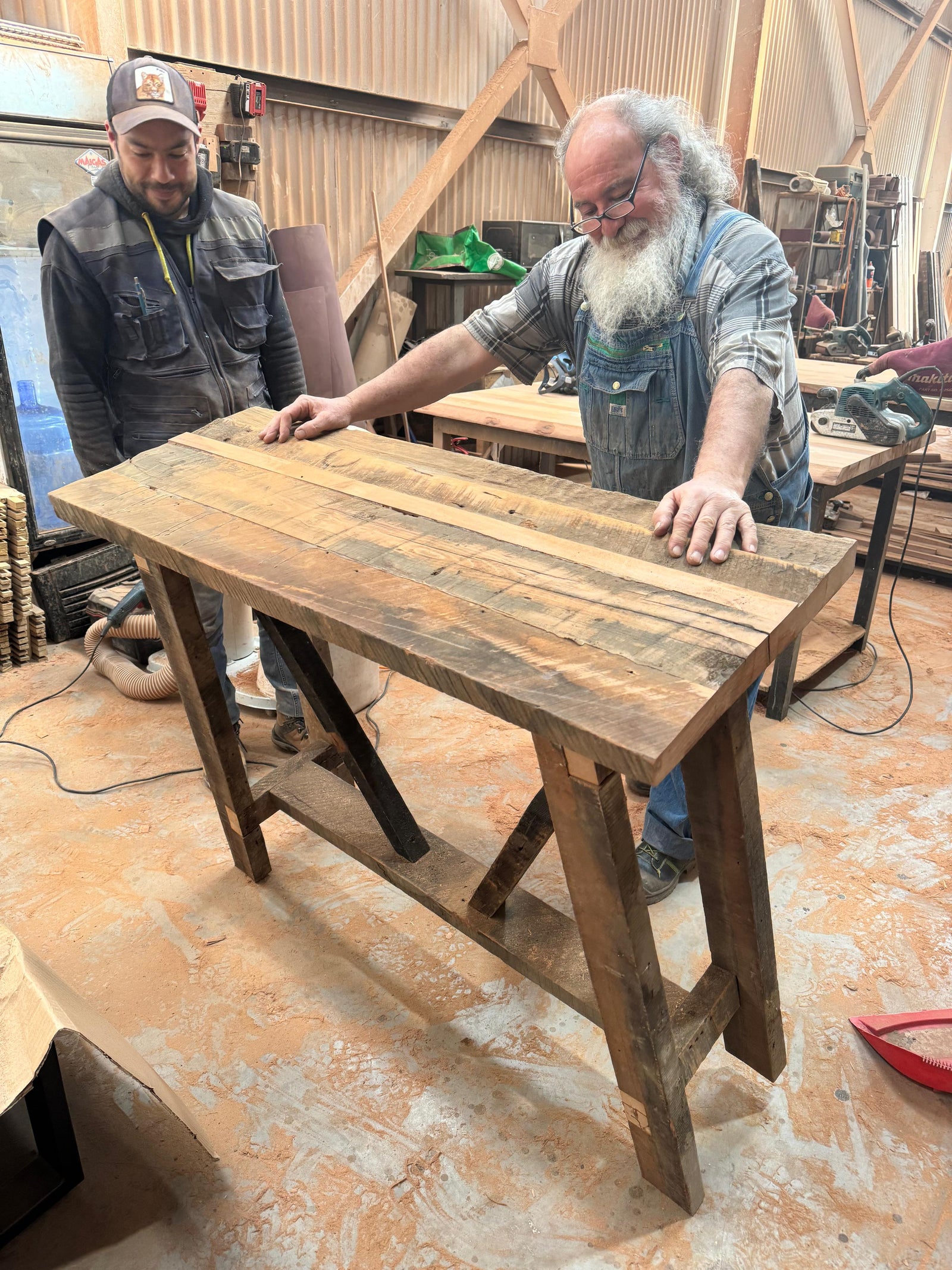 Mesa consola de madera reutilizada con estructura diagonal y diseño robusto.