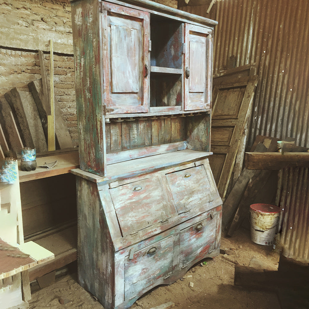 Mueble con puertas superiores en madera reutilizada y repisas interiores funcionales.